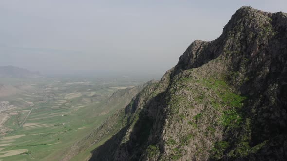 Aerial View of Majestic Rock with Green Vegetation Against Misty Valley at Background