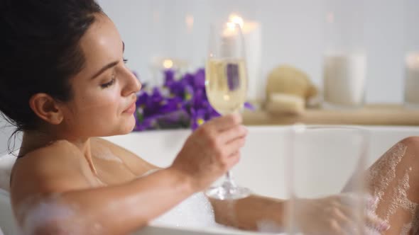 Sexy Woman Washing Legs with Foam in Bath. Girl Drinking Champagne in Bathtub alt