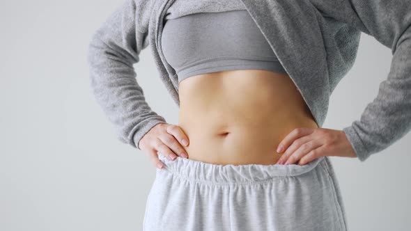 Woman Compressing the Skin on Her Stomach and Sides Checking for Excess Subcutaneous Fat alt