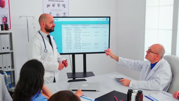 Expert Doctor Presenting to His Team the List of Sick Patients alt