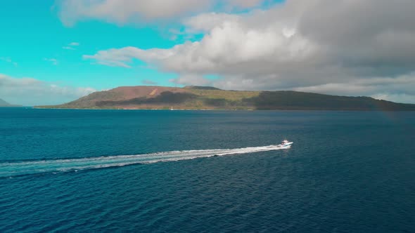 Fishing Boat Sailing Fast on Tropical Sea. Aerial View of Vessel and Coast of Exotic Island alt