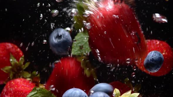 Slow Motion Drop of Blueberries and Strawberries Into Water on Black Background