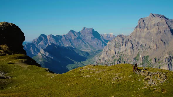 Overflying hikers on mountain pass with high rocky peaks in the background (Grand Muveran massif and alt