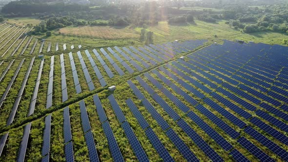 Top view of a massive photovoltaic power station located in a field at sunset alt