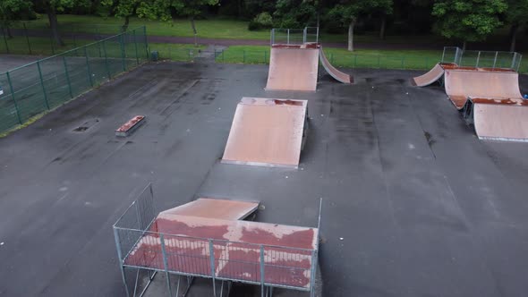 Aerial view flying above fenced skate park ramp in empty closed playground alt