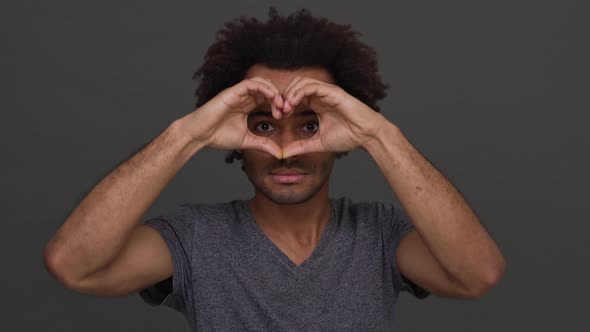African American Cool Man Making Heart with Hands Enjoying Time Isolated on Charcoal Background alt