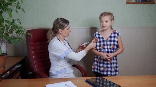 A friendly and kind woman doctor vaccinates a little girl