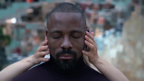 Close-up of an African Face with Closed Eyes on a Mottled Background. a Woman's Fair Skinned Hands alt