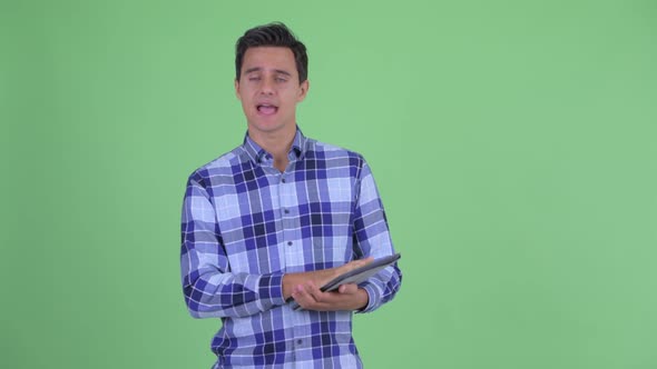 Happy Young Handsome Hipster Man Talking While Using Digital Tablet alt