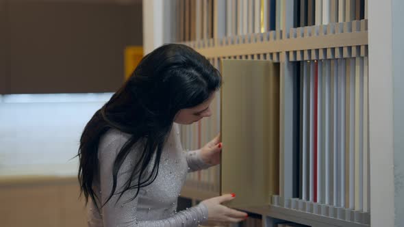 Side View of Confident Concentrated Woman Choosing Kitchen Unit Design Looking at Samples in alt