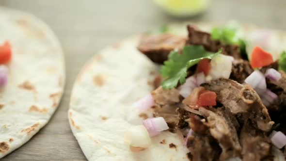 Close up of pulled pork carnitas with pico de gallo on a flour tortilla. alt