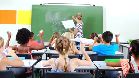 School kids throwing paper balls on teacher in classroom alt