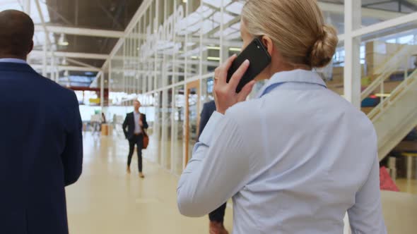 Businesswoman using a smartphone walking in a conference foyer alt