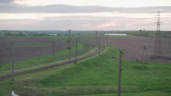 View From Window of Speed Train with Glare on Glass and Parallel Rails on Landscape of Meadows and