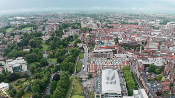 Descending drone shot looking towards York Minster Cathedral over city wall cloudy day alt