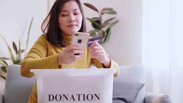 Asian women smile happy are reserving delivery clothing donations to forwarding box. alt