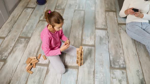 Indifferent Mother Use Mobile Phone Daughter Play Wooden Construction alt
