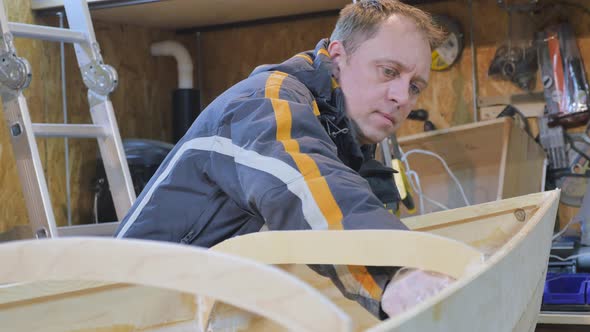 A Man Collects a Boat Made of Wood. He Is Engaged in Manual Labor. alt