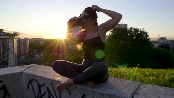 Slow motion shot of young woman using cyber glasses during sunset alt