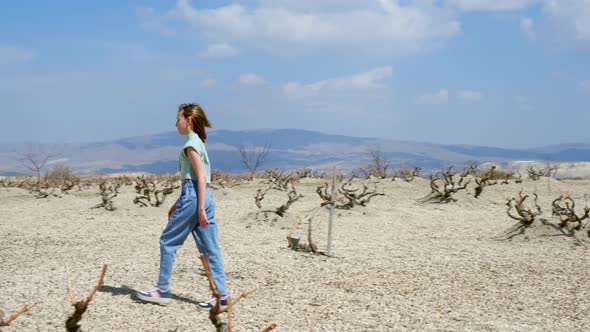 Teen Girl Traveler is Walking in Strange Valley Desert Landscape at Sunny Day