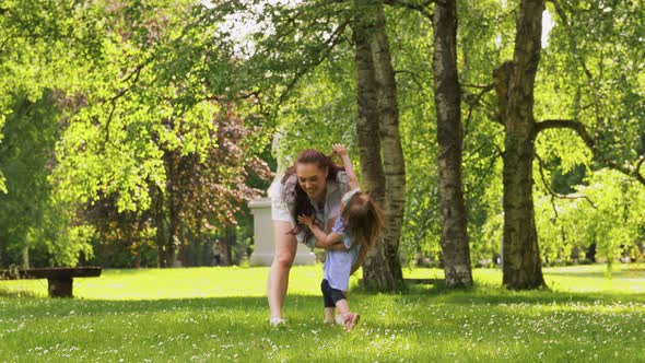 Happy Mother with Little Daughter Playing at Park