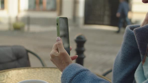 Elderly Woman Using Mobile Phone App for Online Video Call Outdoors alt