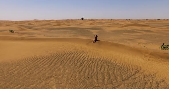 Girl Sitting on a Dune in the Desert