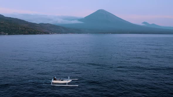 Peaceful Sunrise Landscape with a Distant Volcano Mountain Color Blue Pink and Jukung Motorboat on