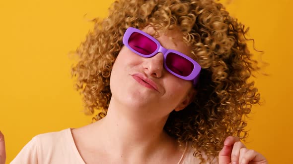 Happy Optimistic Young Woman in Stylish Veri Pery Color Glasses Raises Arms and Dances to Favorite