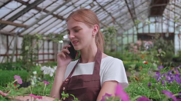 Close Up Portrait of Beautiful Joyful Female Florist Store Manager Talking on Cellphone About Plant