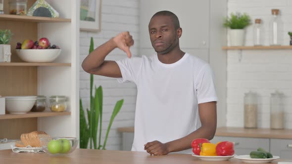 Sporty African Man Showing Thumbs Down While Standing in Kitchen alt