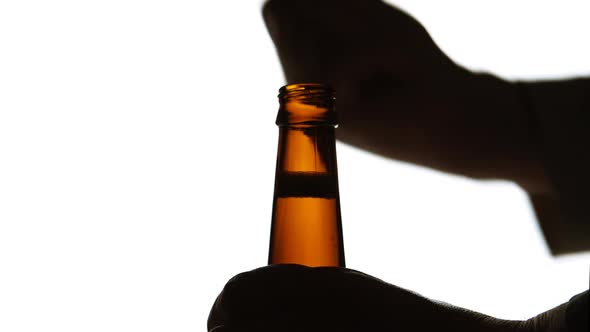 The Silhouette of Male hands opening brown beer bottle