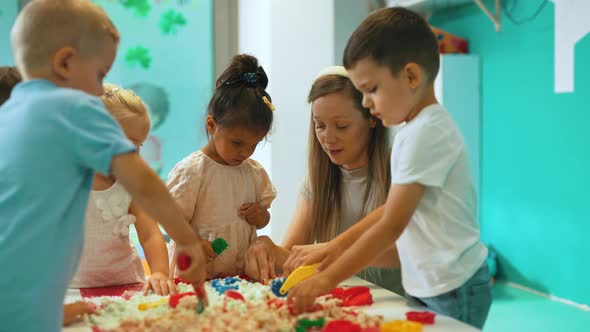 Caucasian Teacher and Her Children Making Figures From the Kinetic Sand alt