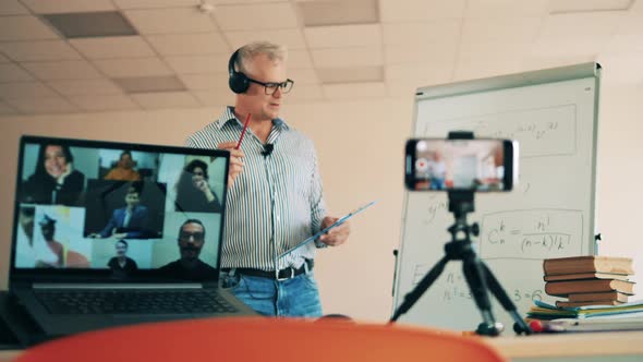 A Man Is Teaching Adult Students an Online Class About Formuals alt