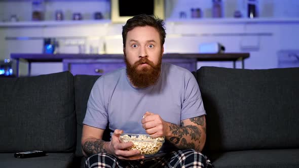 Man eating popcorn and watching tv.