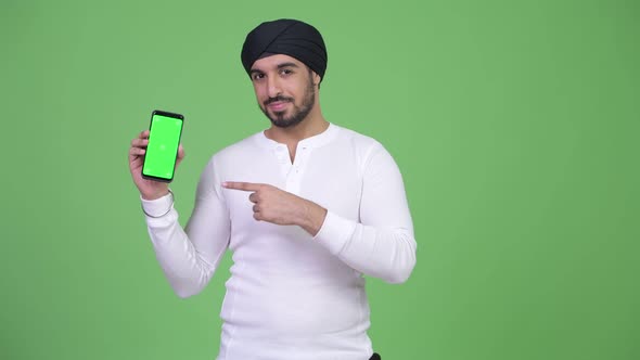 Young Happy Bearded Indian Man Showing Phone and Giving Thumbs Up