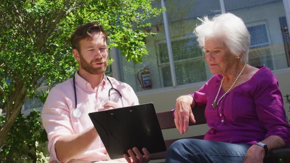 Doctor with a senior woman in the park of a retirement home alt