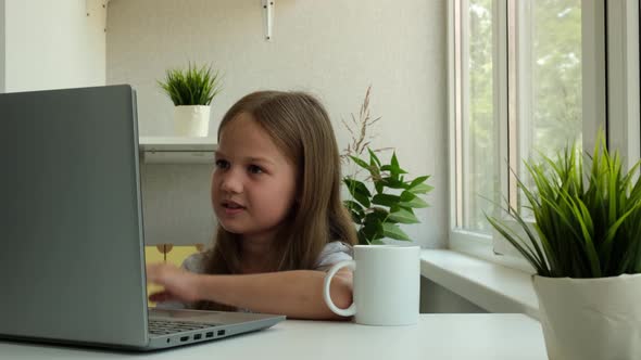 Child Girl is Using a Laptop and Study Online at Home alt