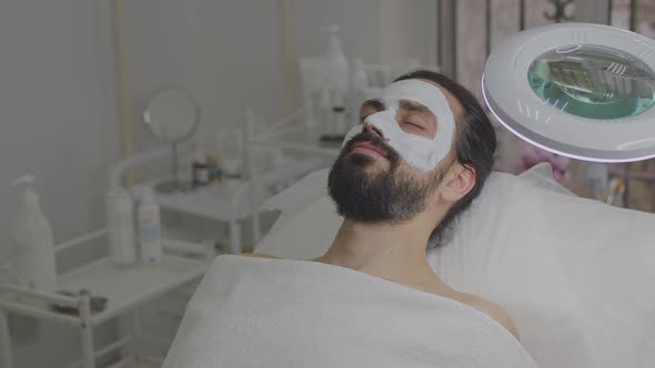 Closeup of a Young Man's Face with a Cleansing White Mask on His Face alt