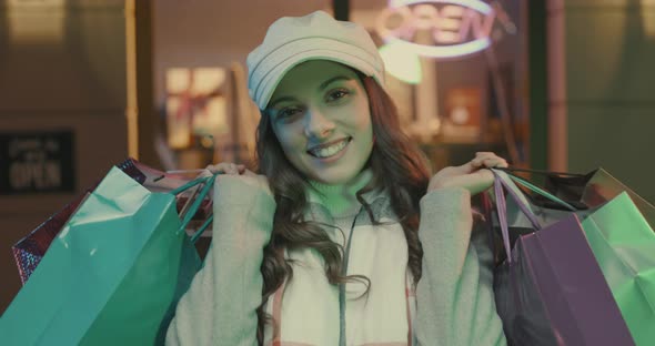 Young woman walking in the city streets and carrying shopping bags, she is happy and smiling