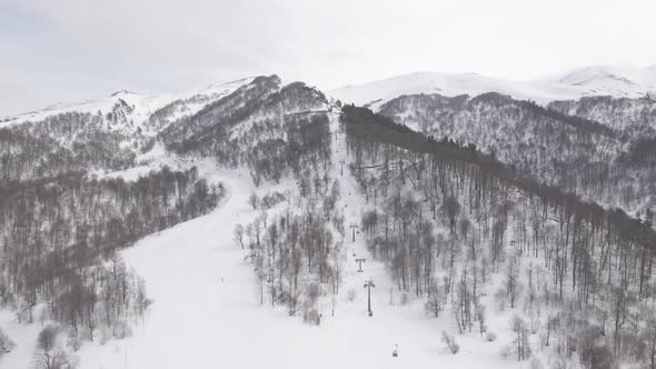 Flying over rope-way with gondolas at mountain resort Crystal Park in Bakuriani. Snowy winter day. alt