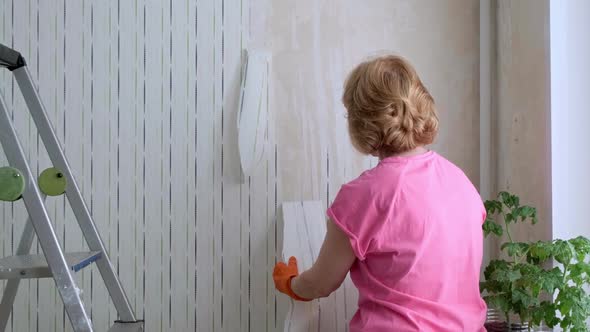 Woman Removing Old Wallpaper From Walls Preparing for Flat Renovation alt