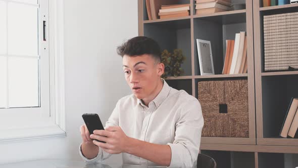 Overjoyed caucasian ethnicity teenager sit at desk looks at phone screen read incredible news alt