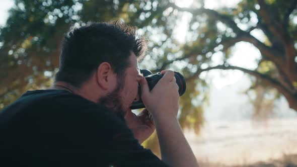 Back View of Professional Photographer Taking Pictures in Nature Park at Sunset alt