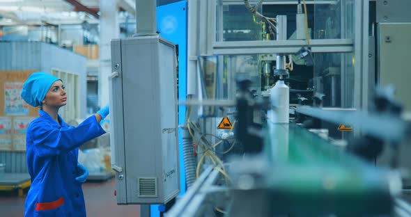 Girl Tunes the Work of the Conveyor for the Production of Plastic Bottles alt