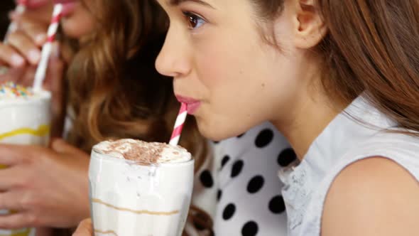 Female friends having smoothie with straw alt