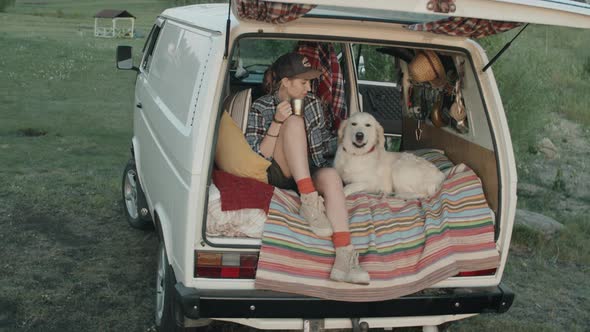 Woman and Dog Sitting in Camper Van with Opened Door alt