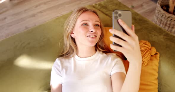 Young woman making video call or chat online on mobile phone at home alt