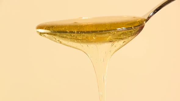 Honey flowing from metal spoon alt