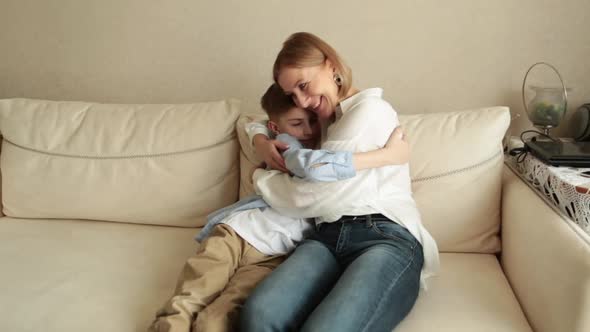 Adult Woman Sits with a Teenager on the Couch Chatting and Hugging